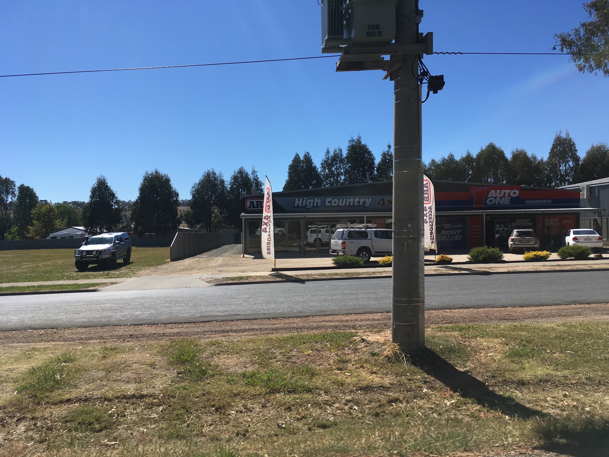 The shopfront seen from across Mt Buller Road, with ARB feather flags at the kerb